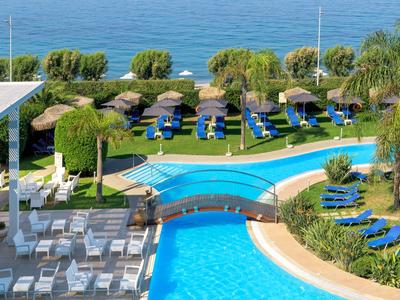 Hotelpool mit Brücke, Liegen und Meerblick in tropischer Umgebung