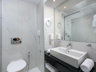 Modern hotel bathroom with white sink, toilet, and large mirror.
