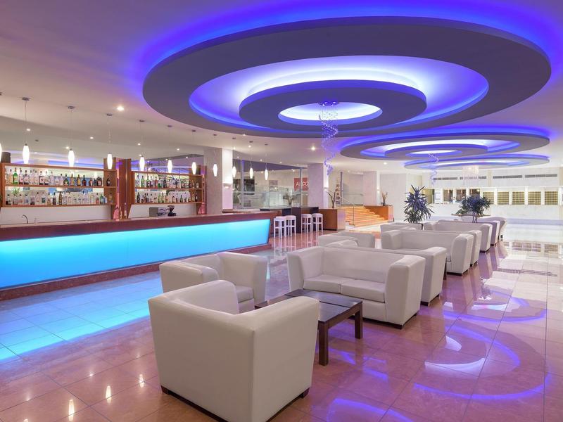 Moderna hall dell'hotel con mobili bianchi e bancone della reception illuminato di blu.