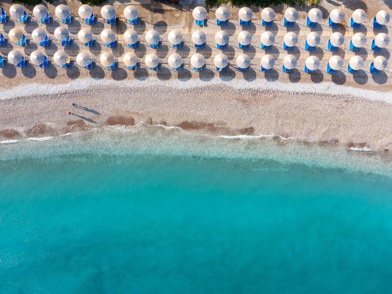 Spiaggia con file di ombrelloni blu e acqua turchese