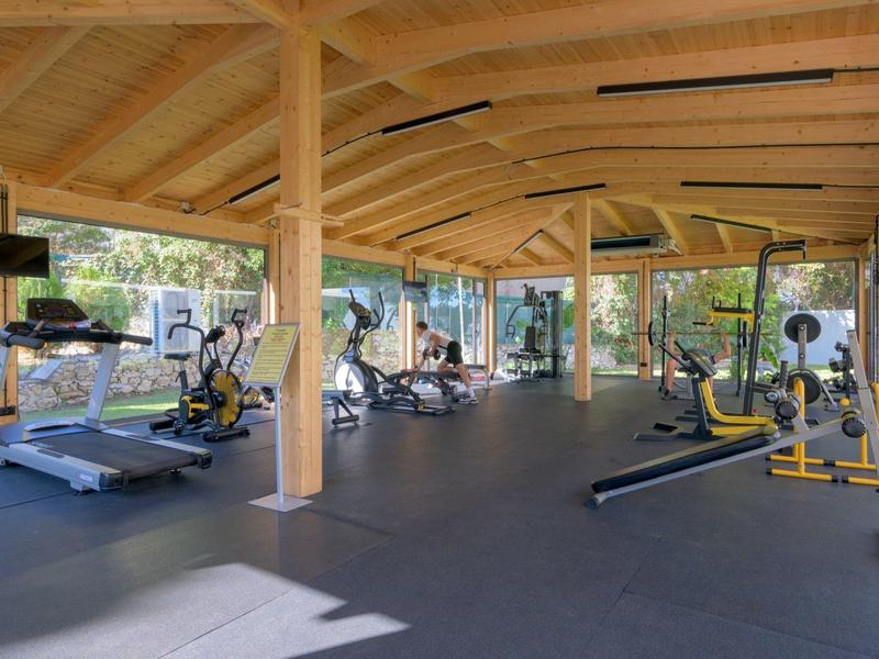 Palestra luminosa con grandi finestre e attrezzature moderne in una struttura in legno.