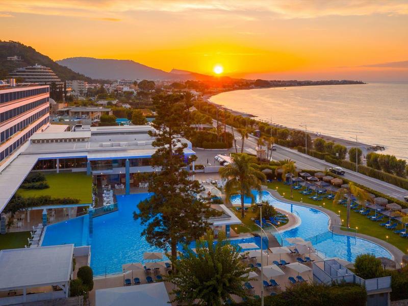 Hotel con grande piscina vicino al mare al tramonto.