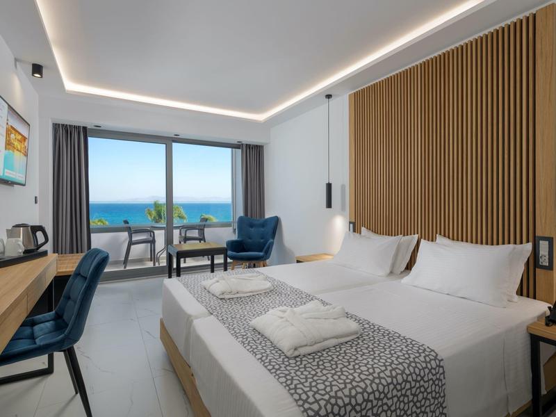 Camera d'hotel moderna con letto matrimoniale, zona soggiorno e balcone con vista mare.