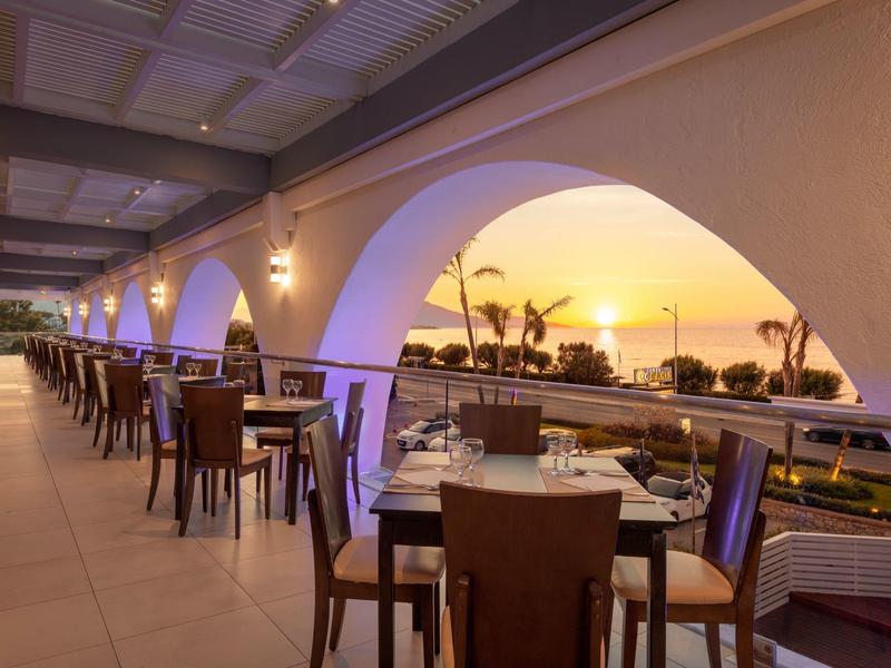 Terrazza con tavoli e sedie con vista sul mare al tramonto in un hotel