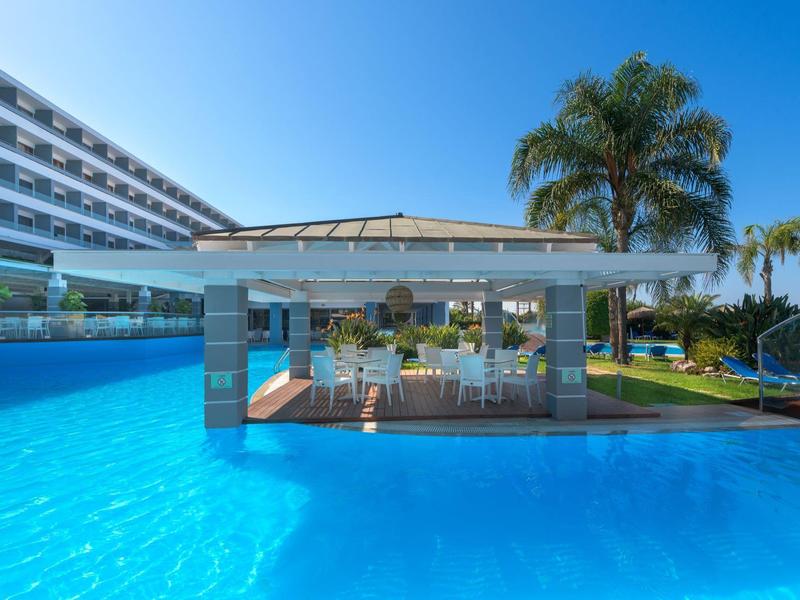 Pool bar all'aperto in un hotel con acqua azzurra limpida e palme