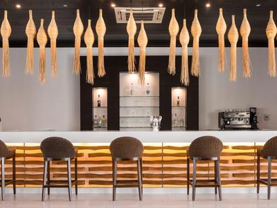 Bar moderno con sgabelli e illuminazione sospesa in un interno elegante e minimalista.