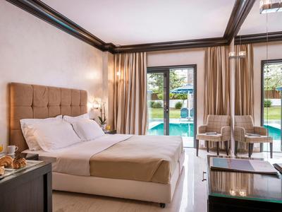 Camera d'hotel luminosa con letto matrimoniale, terrazza e piscina visibile all'esterno.