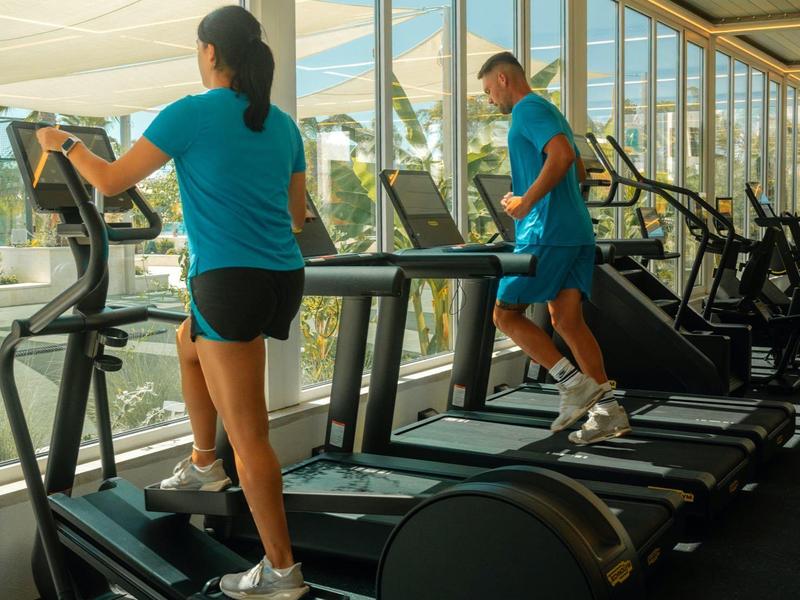 Due persone fanno cardio su tapis roulant in una palestra luminosa con vista.