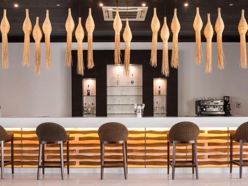 Bar moderno con sgabelli e illuminazione sospesa in un interno elegante e minimalista.