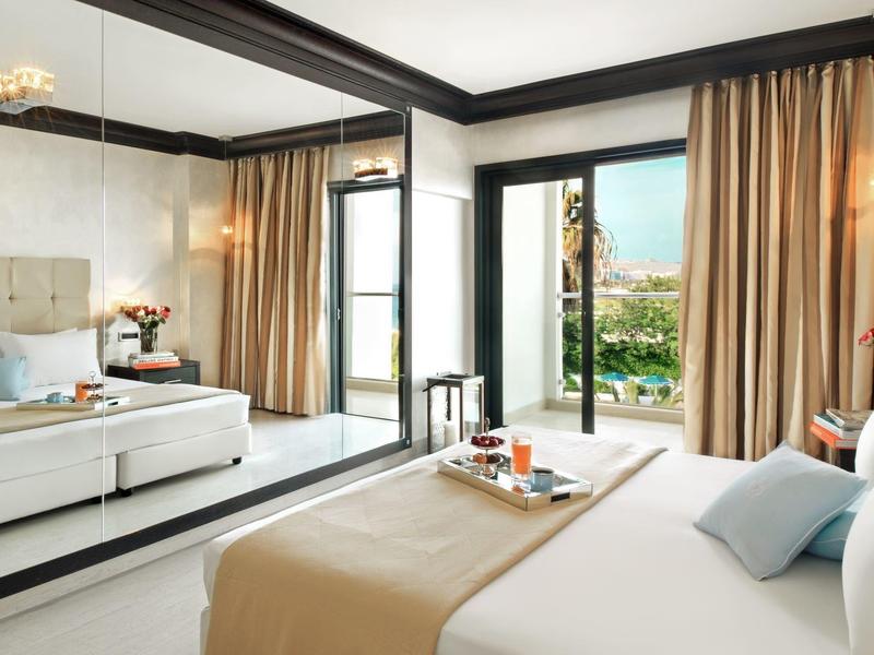 Camera d'hotel luminosa con letto, divano, ampie finestre e vista sul giardino.