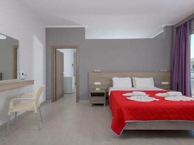 Modern hotel room with double bed, red bedspread, desk, and window view.