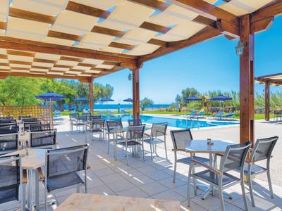 Überdachte Terrasse mit Tischen und Stühlen neben blauem Pool und sonnigem Himmel.