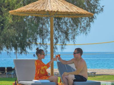 Ein Paar sitzt unter einem Strohmantel am Pool und genießt die Aussicht auf das Meer.