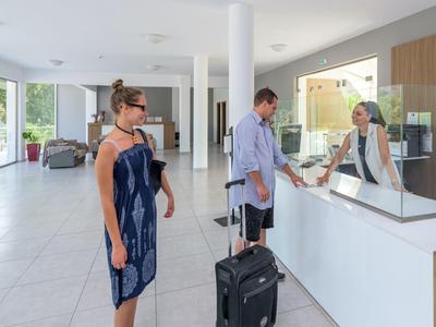 A couple checks in at the reception of a modern hotel with bright floors and minimalist decor.