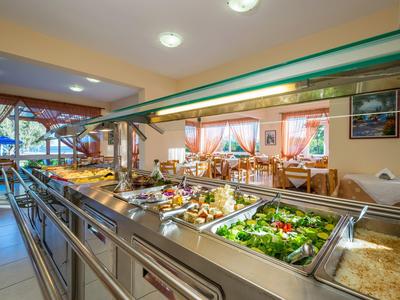 Buffet area with salads and various dishes in a bright restaurant with wooden decor.