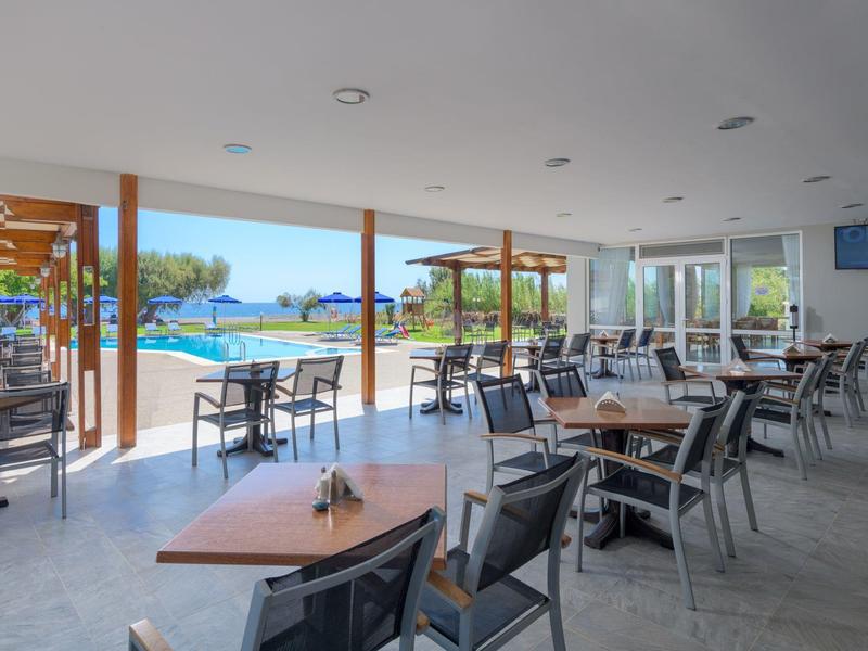 Open dining area with views of swimming pool and sea in the background.