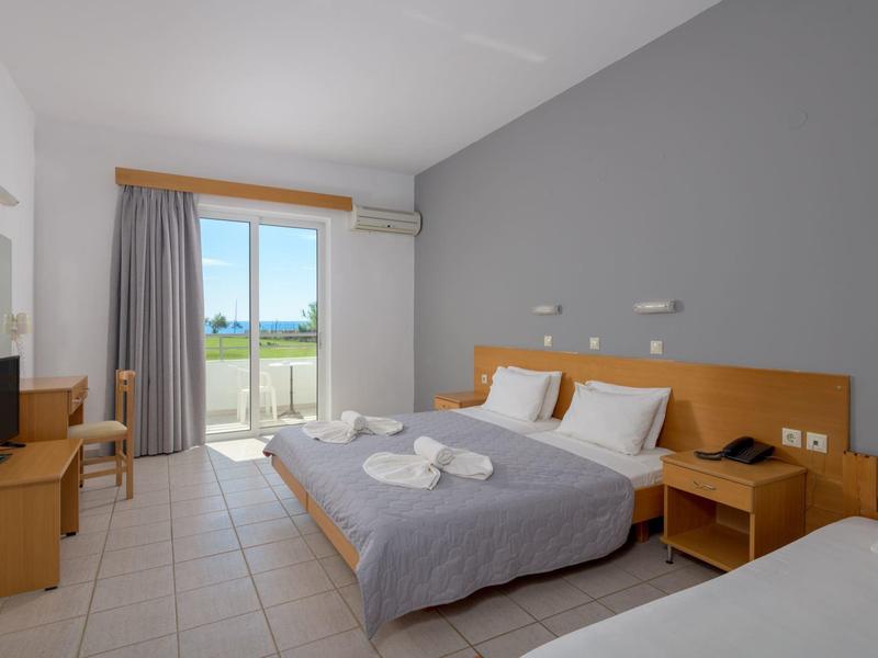 Modern hotel room with double bed, single bed, balcony, and TV.