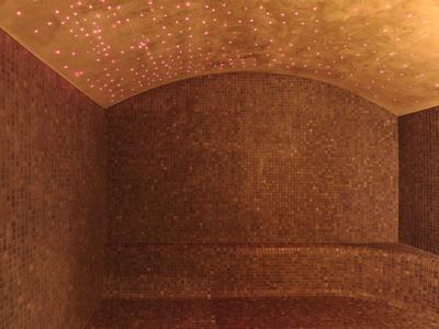 Sala de baño de vapor cálido con azulejos de mosaico y techo curvado para relajación en el spa.