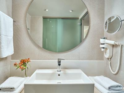 Baño moderno con espejo redondo, toallas y secador de pelo en la pared.