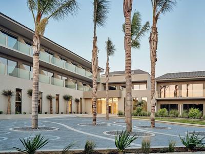Complexe hôtelier moderne avec palmiers et cour ouverte en plein jour
