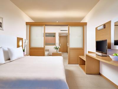 Habitación de hotel luminosa con cama doble, muebles de madera y un gran espejo en la pared.