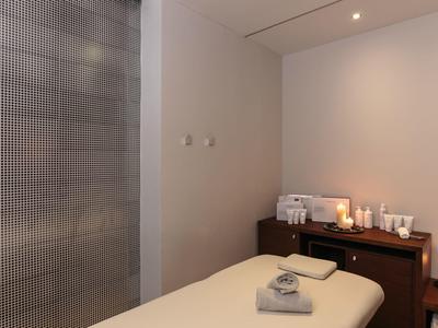 Acogedora sala de bienestar con camilla, toallas y velas para un ambiente relajante.