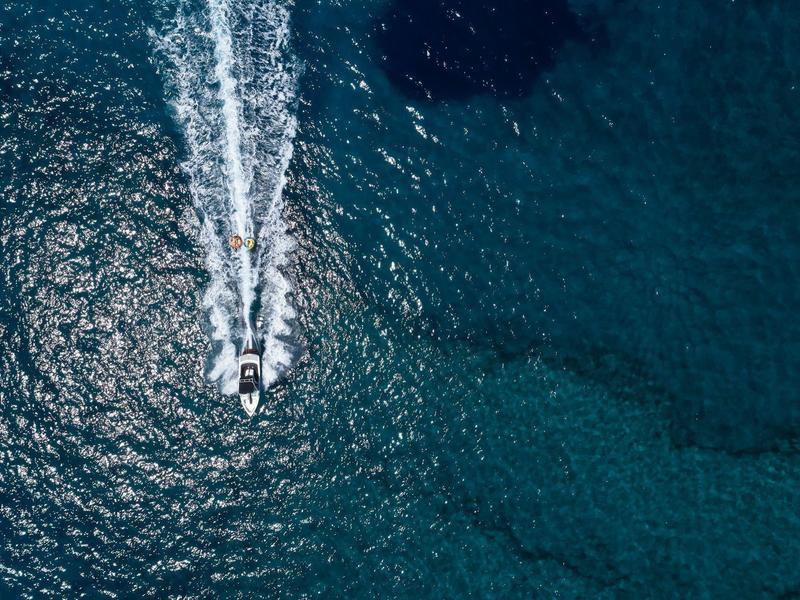 Vista aérea de una moto acuática moviéndose sobre el agua clara y azul