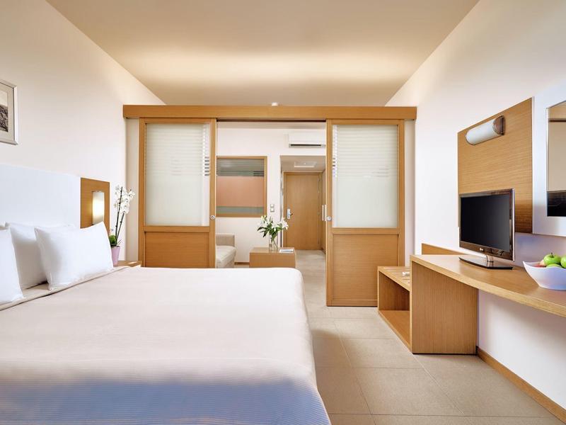 Habitación de hotel luminosa con cama doble, muebles de madera y un gran espejo en la pared.