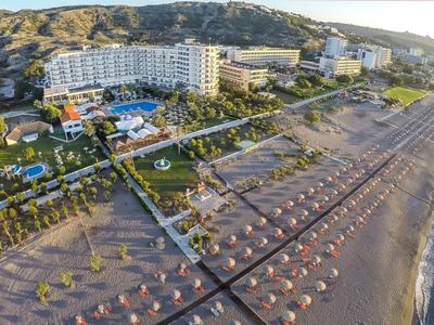 Aerial view of a beachfront hotel with pool and umbrellas on the sandy beach