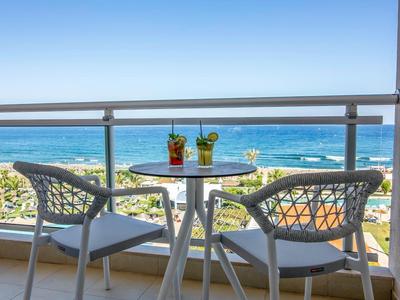 Balcony with table, two chairs, and drinks overlooking the sea.