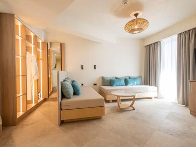Modern hotel room living area with sofas, coffee table, and large glass front.