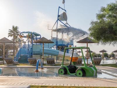 Wasserpark mit Rutschen, Schirmen und Grünflächen bei sonnigem Wetter.