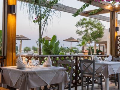 Elegantes, offen gelegenes Restaurant mit gedeckten Tischen und Blick auf tropische Pflanzen und Meer.