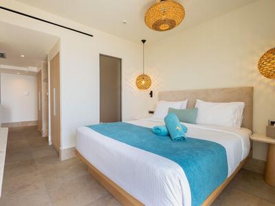 Modernes Hotelzimmer mit Doppelbett, weißen Wänden und türkisen Akzenten.