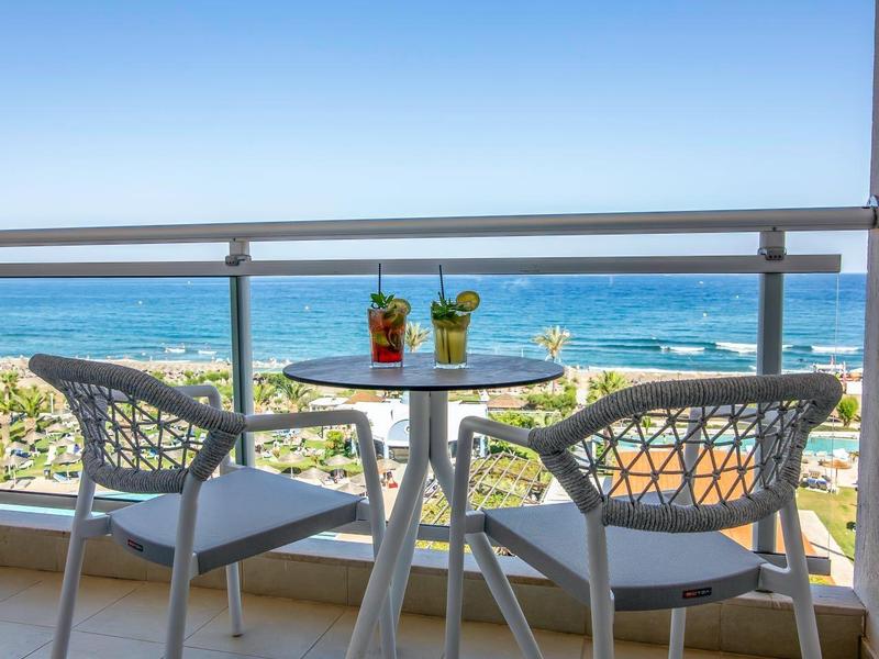 Balcony with table, two chairs, and drinks overlooking the sea.