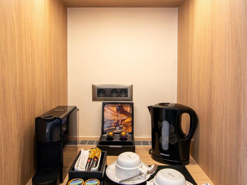 Coffee and tea station in a wooden niche with cups and accessories.