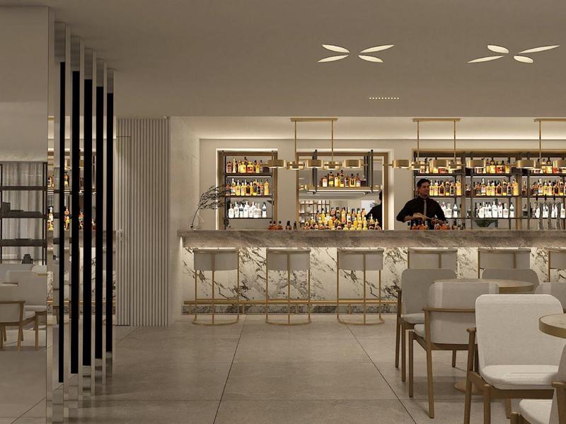 Modern hotel bar area with elegant chairs and illuminated counter in bright interior.