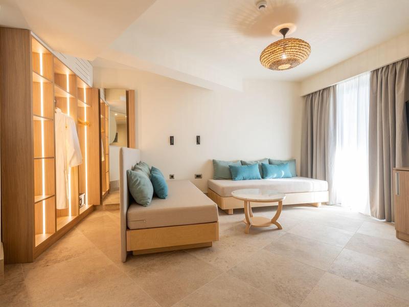 Modern hotel room living area with sofas, coffee table, and large glass front.
