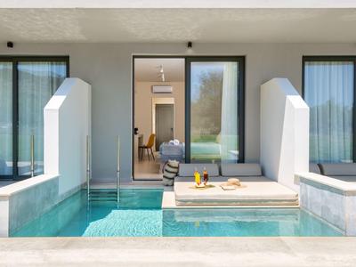 Moderní bazén s posezením před dvěma pokoji s velkými okny a závěsy.