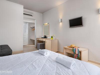 Světý hotelový pokoj s manželskou postelí, psacím stolem, televizí a přístupem do koupelny.