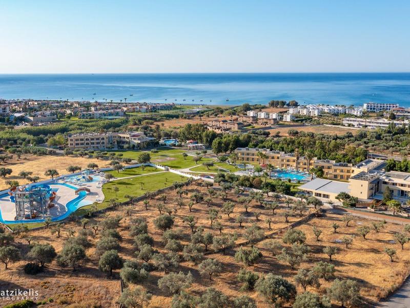 Letecký pohled na pobřežní hotel s bazény, olivovými háji a výhledem na moře