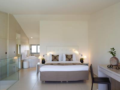 Modernes Schlafzimmer mit großem Bett, zwei Nachttischen, Schreibtisch und heller, ruhiger Atmosphäre.