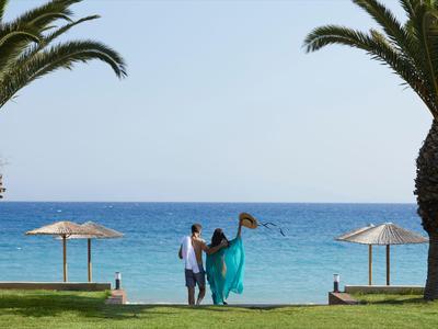 Para z turkusową suknią nad morzem między palmami i parasolami