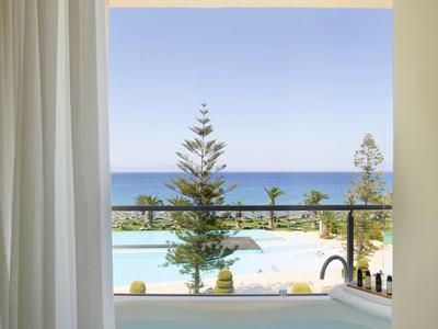 Vírivka na balkóně s výhledem na moře a palmy za jasné oblohy