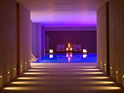 Flur mit indirekter Beleuchtung führt zu einem innenliegenden Pool mit stimmungsvoller blauer Lichtbeleuchtung.