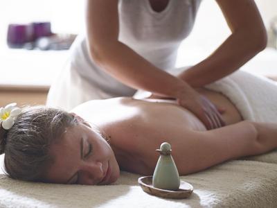 Frau entspannt bei Massage in Spa-Umgebung mit Aromatherapie-Duftöl.