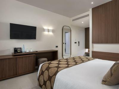 Modernes Hotelzimmer mit großem Bett, Fernseher an der Wand und Holzmöbeln.