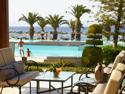 Widok na basen z leżakami i palmami w tle w słoneczny dzień.