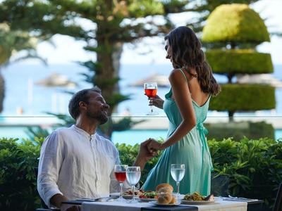 Para delektująca się napojami przy nakrytym stole z widokiem na morze w luksusowym miejscu wakacyjnym.