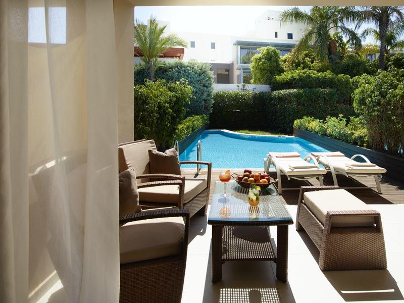 Gemütliche Lounge-Ecke mit Blick auf einen privaten Pool und Liegestühle in einem Garten.